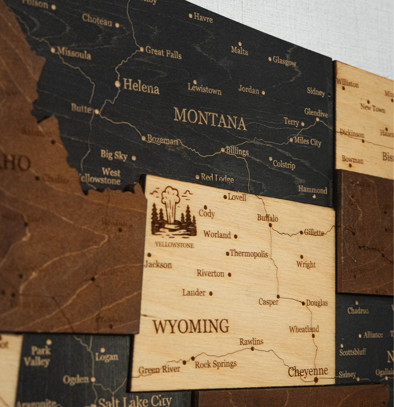 Wooden map of Montana and Wyoming with engraved text and small illustrations.