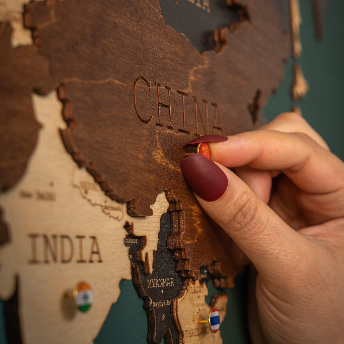 Hand pinning China on a 3d Wooden World map