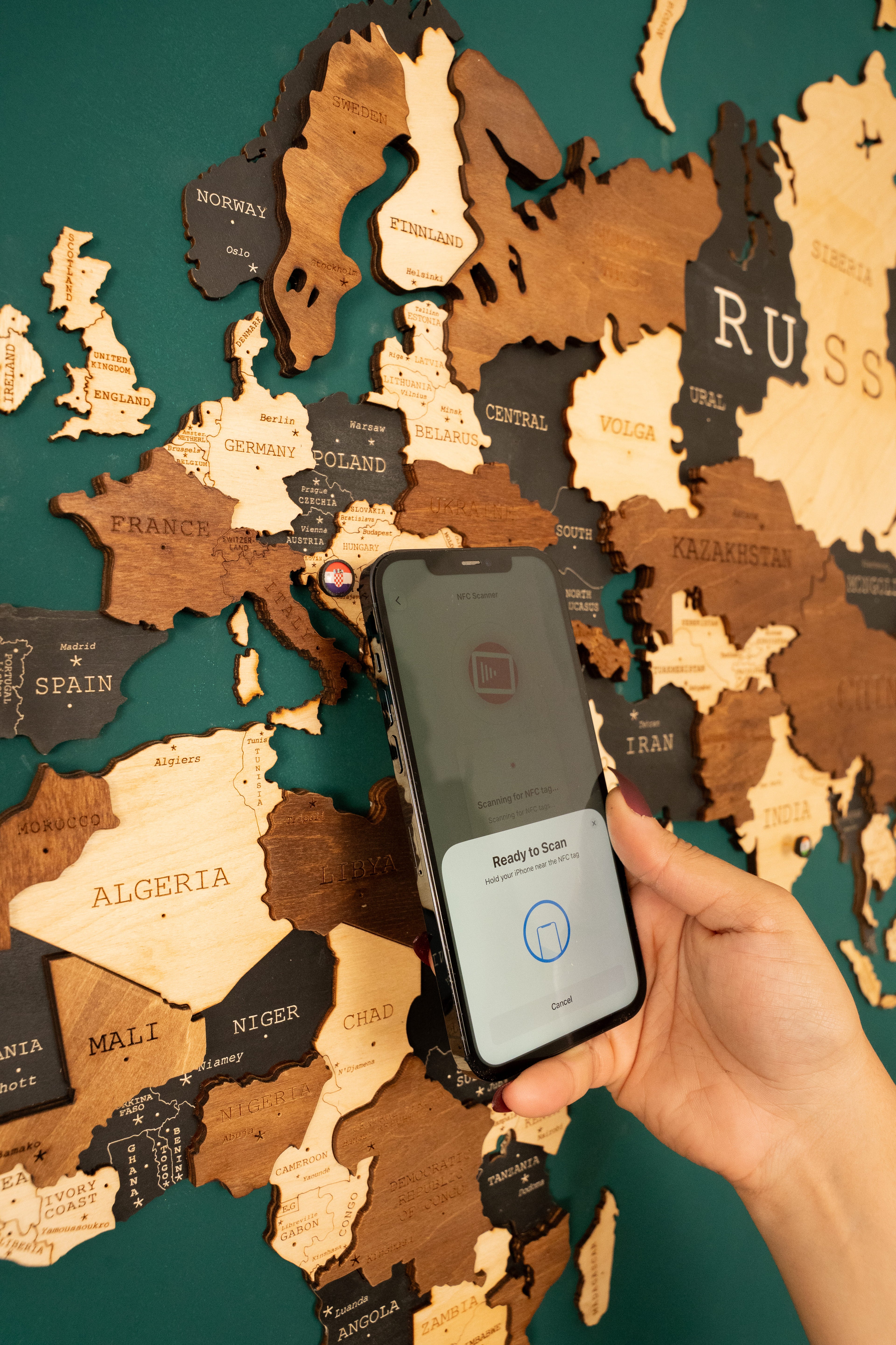 Hand holding a smartphone with a map of the world in the background