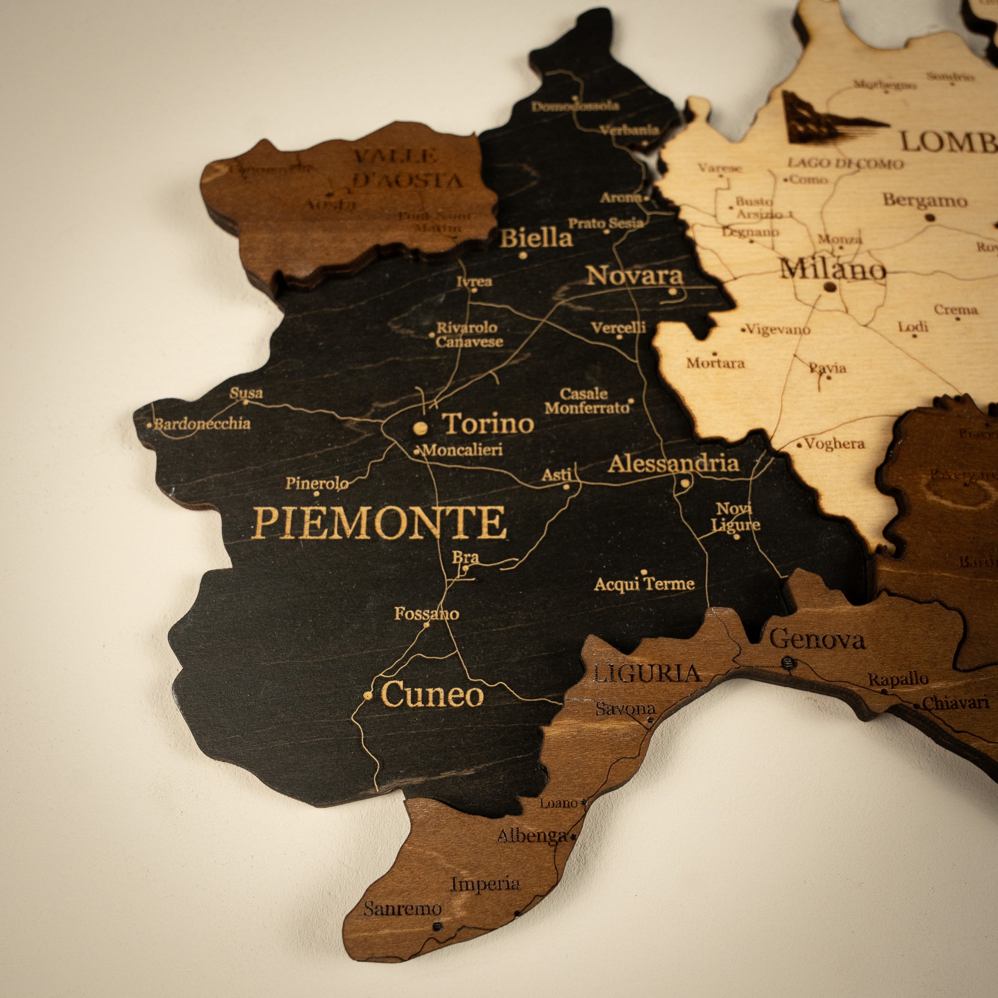 Wooden map of Piemonte with cities labeled on a beige background